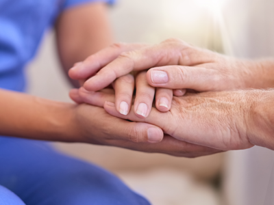 A doctor holds hands with an elderly patient