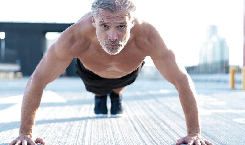 Middle-aged man posing in the middle of doing pushups to keep his heart healthy with regular exercise.